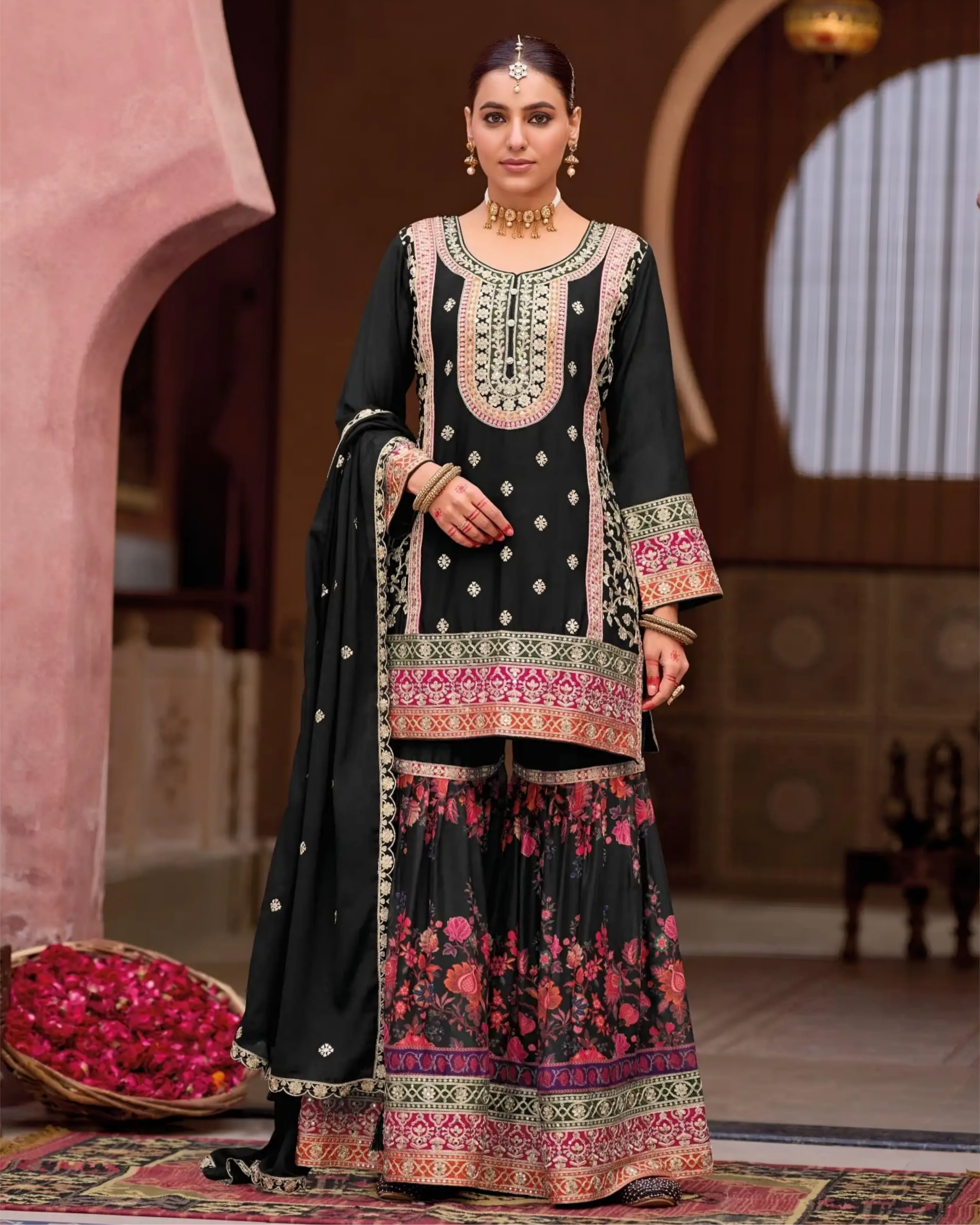 Woman in traditional black and pink embroidered outfit with a decorative background