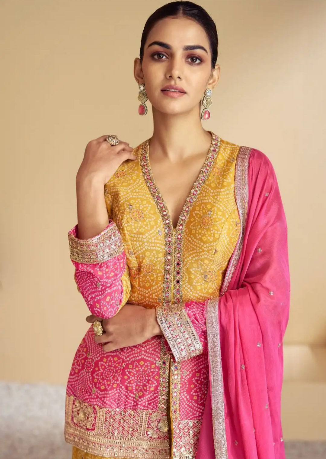 Woman wearing a traditional outfit with a yellow and pink design against a beige background