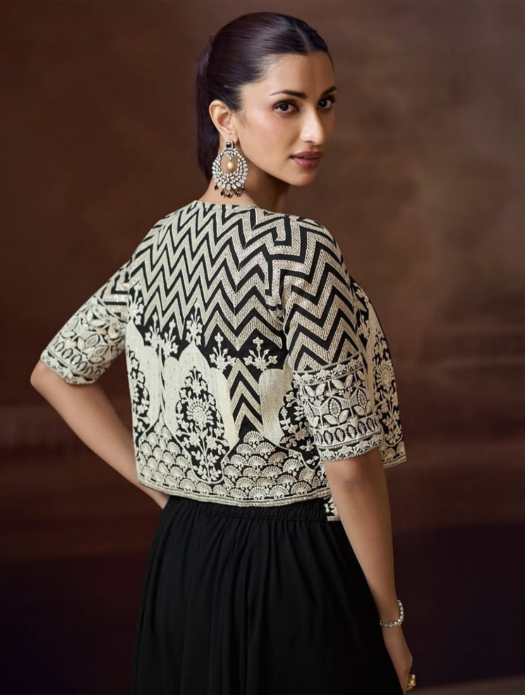 Woman wearing a black and white patterned top with a brown background