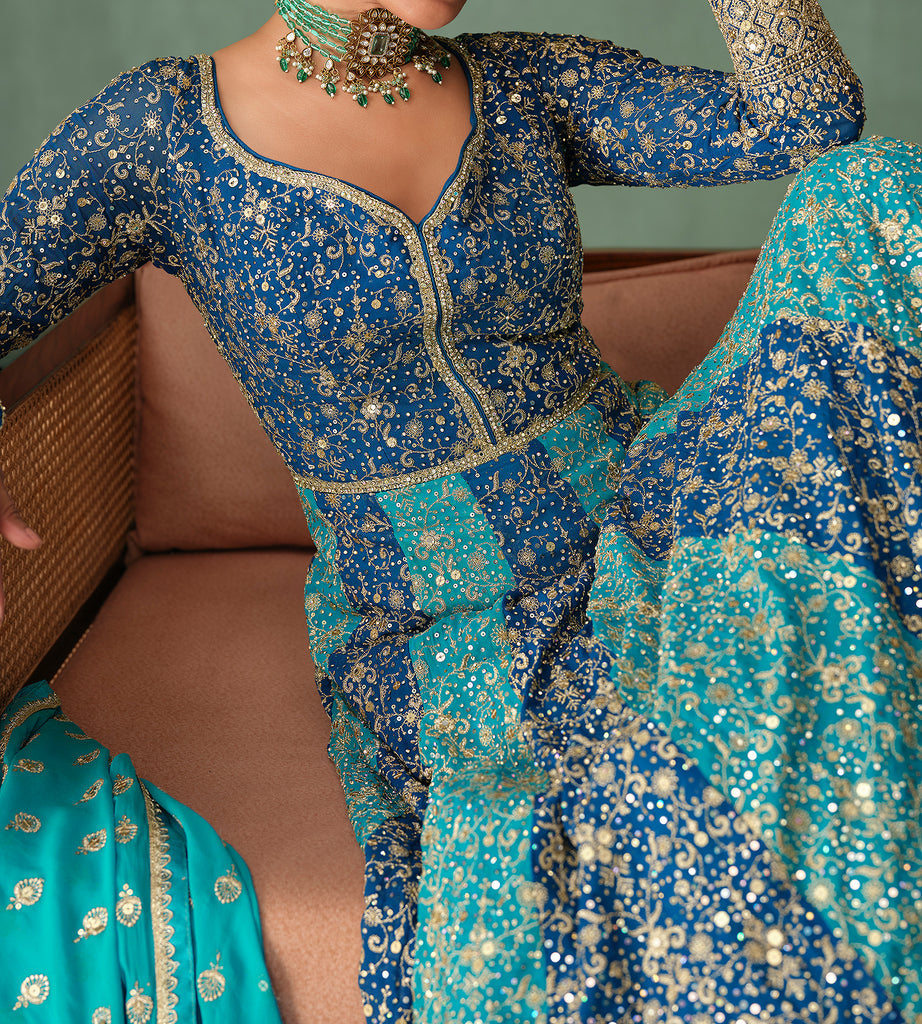 Traditional blue and turquoise embroidered outfit with jewelry on a neutral background