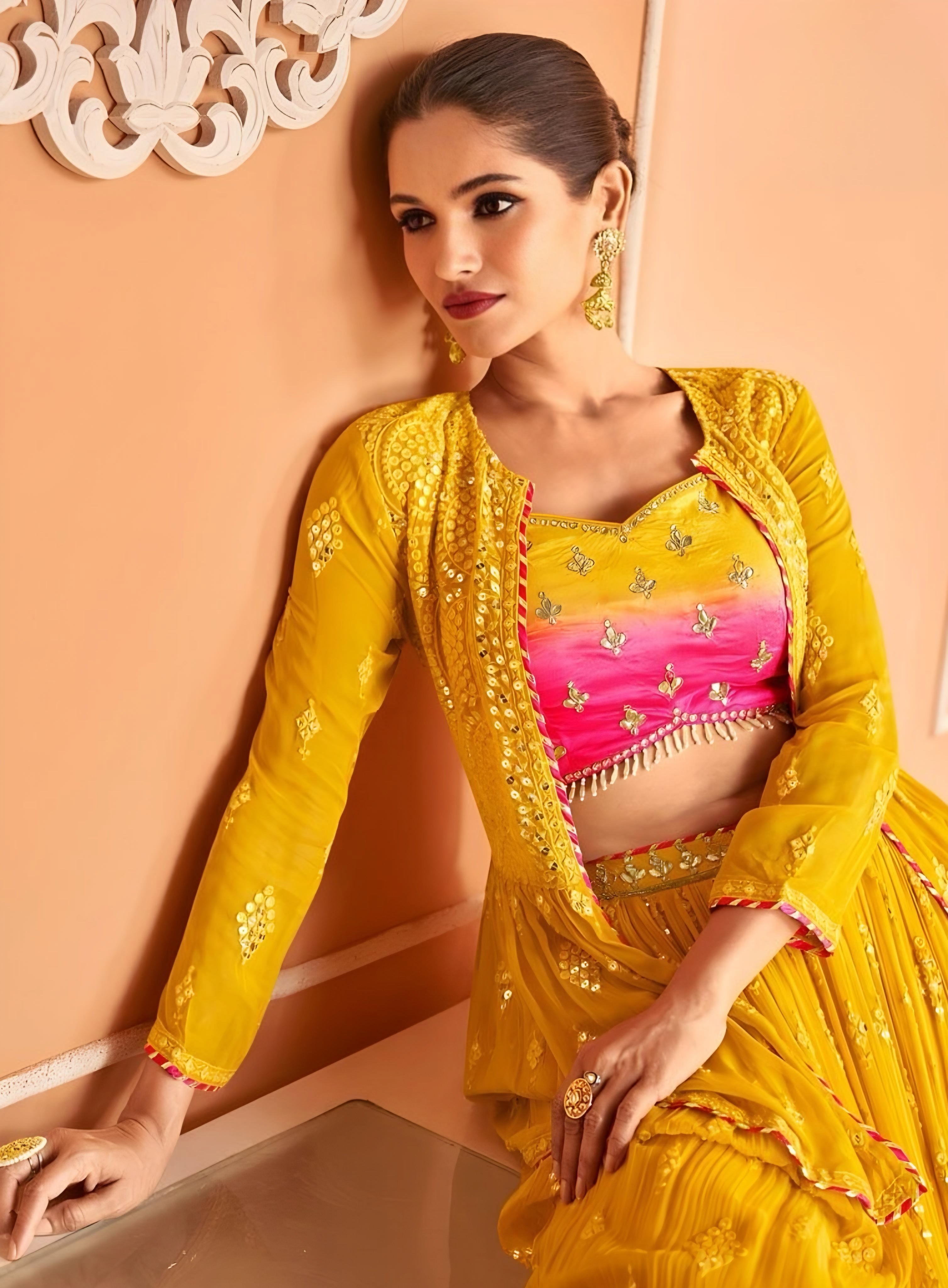 Close-up of mustard yellow lehenga jacket and contrasting pink embroidered blouse