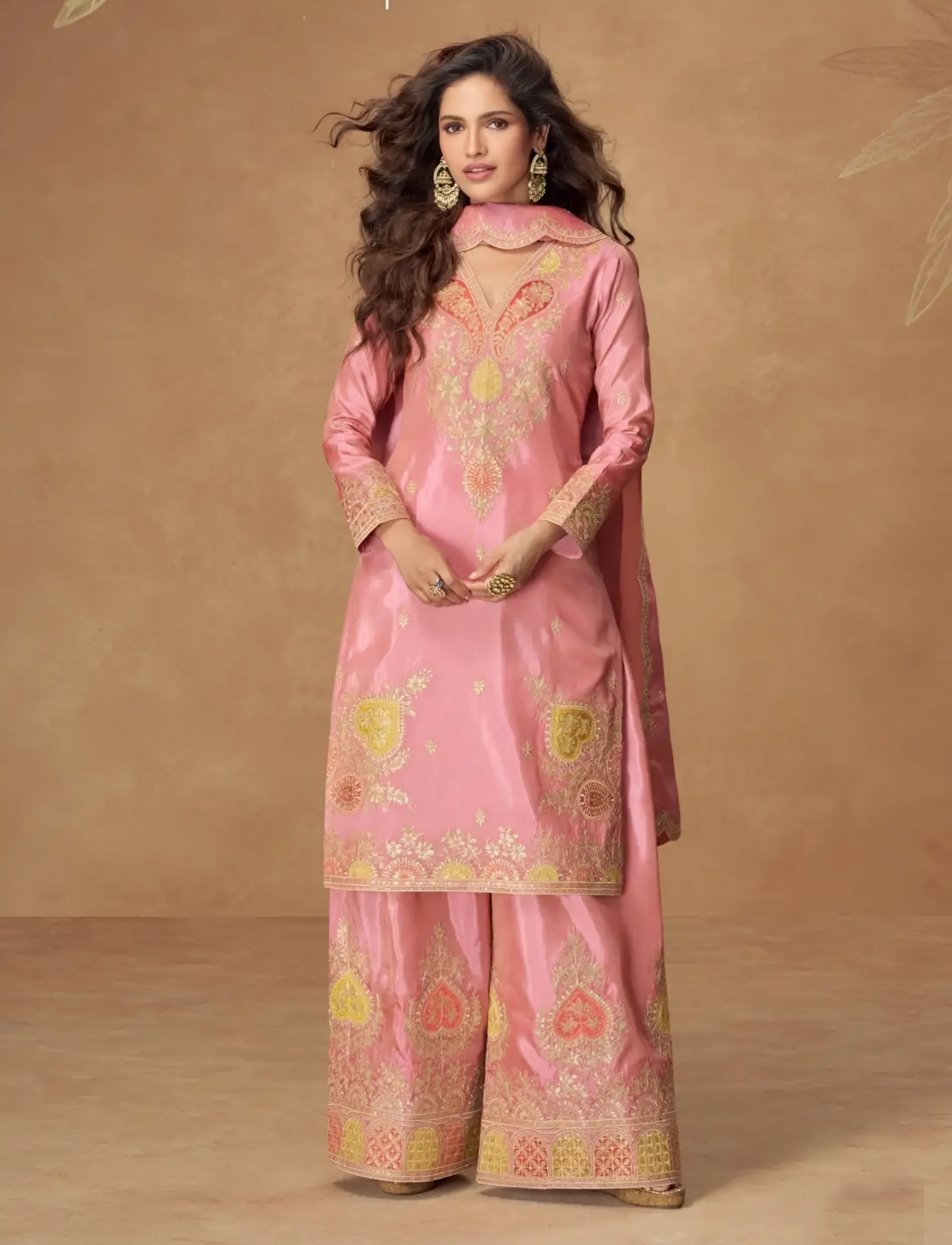 Woman wearing a pink traditional outfit with floral patterns on a brown background