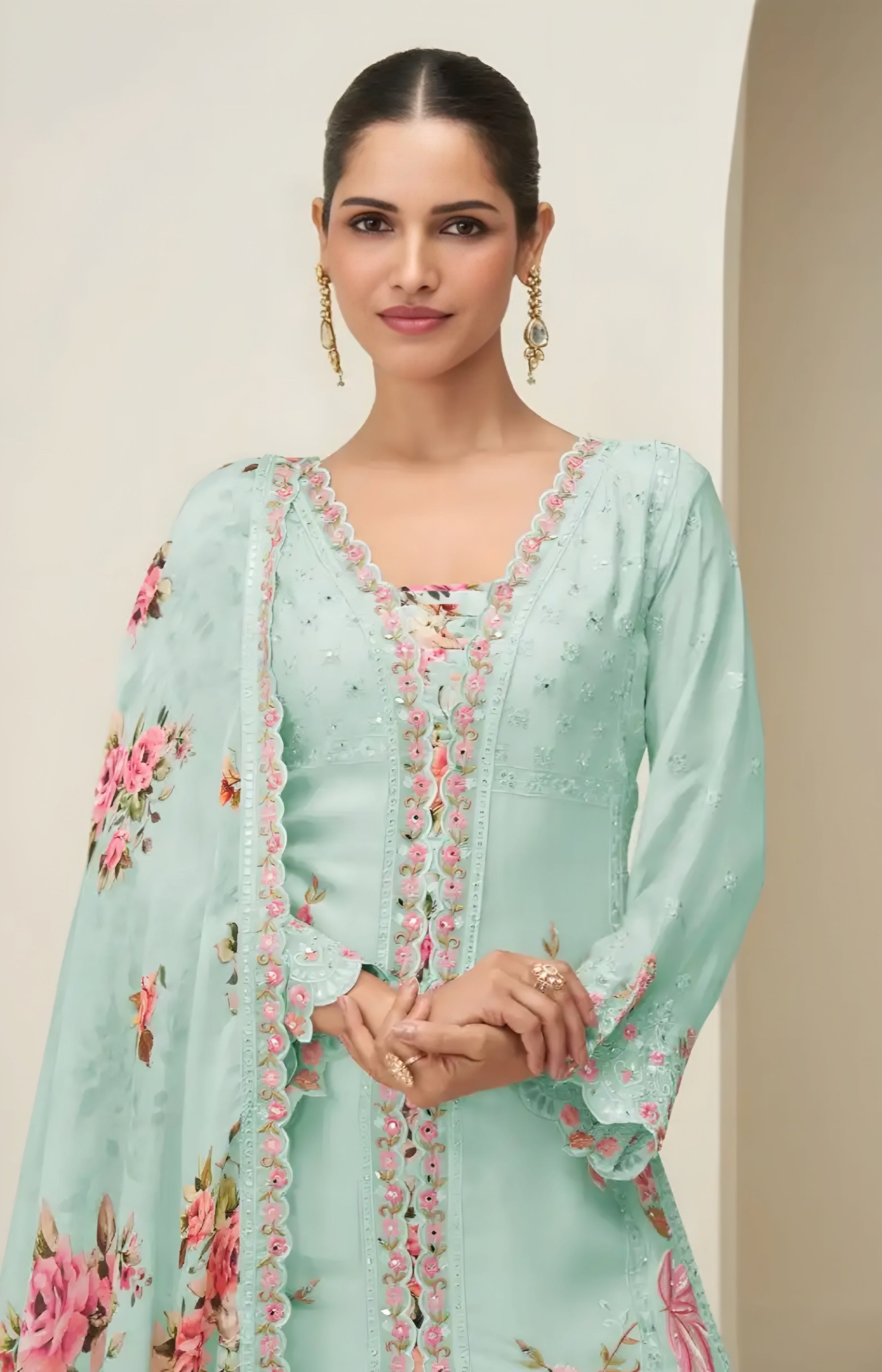 Woman wearing a light blue embroidered dress with floral patterns on a neutral background