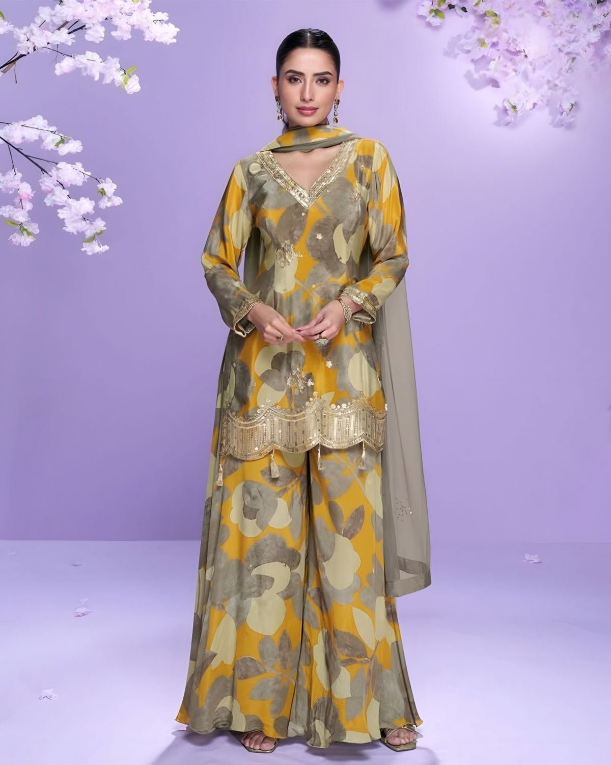 Woman wearing a floral salwar kameez with a purple background and cherry blossoms.