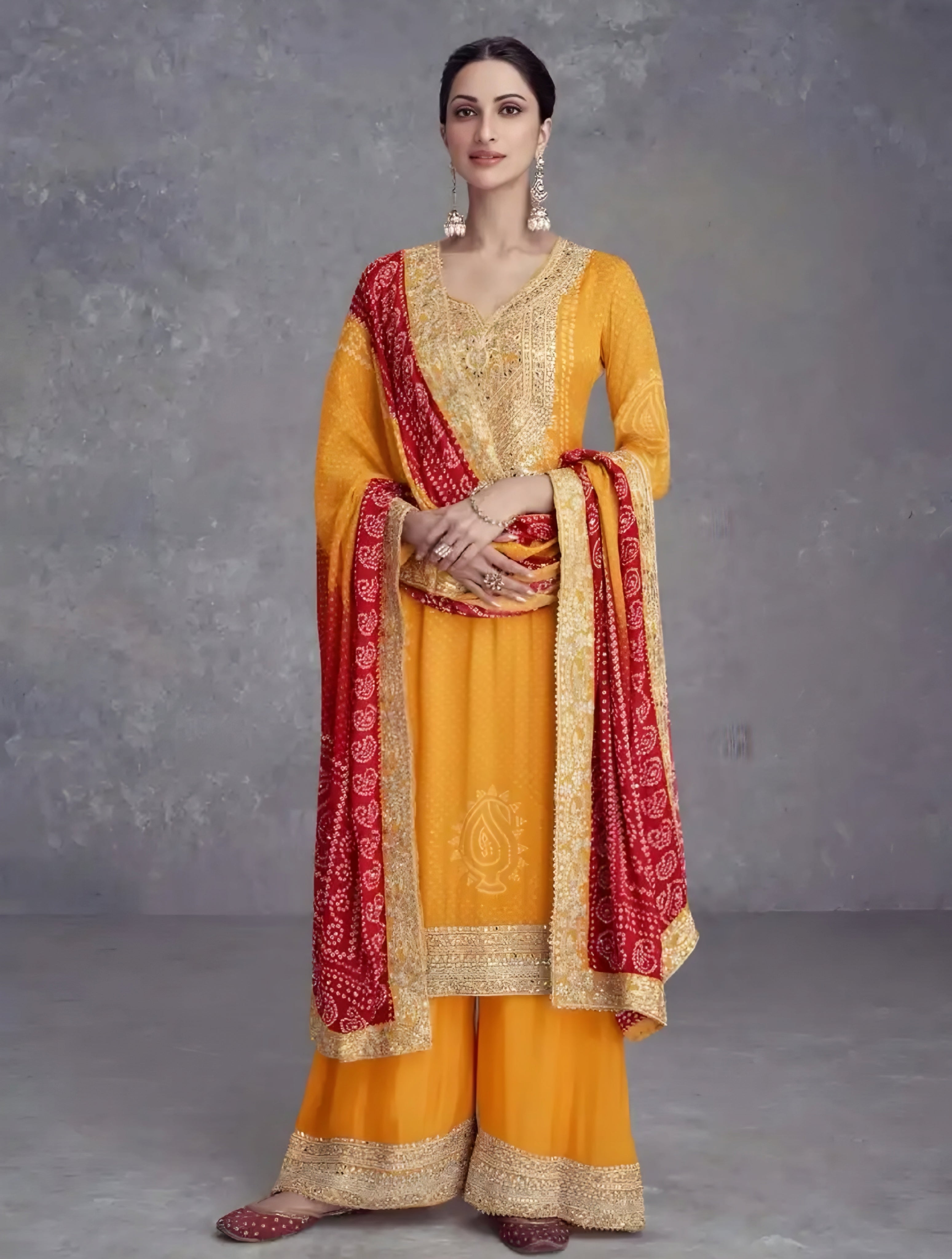 Woman wearing a yellow traditional outfit with red and gold accents against a gray background