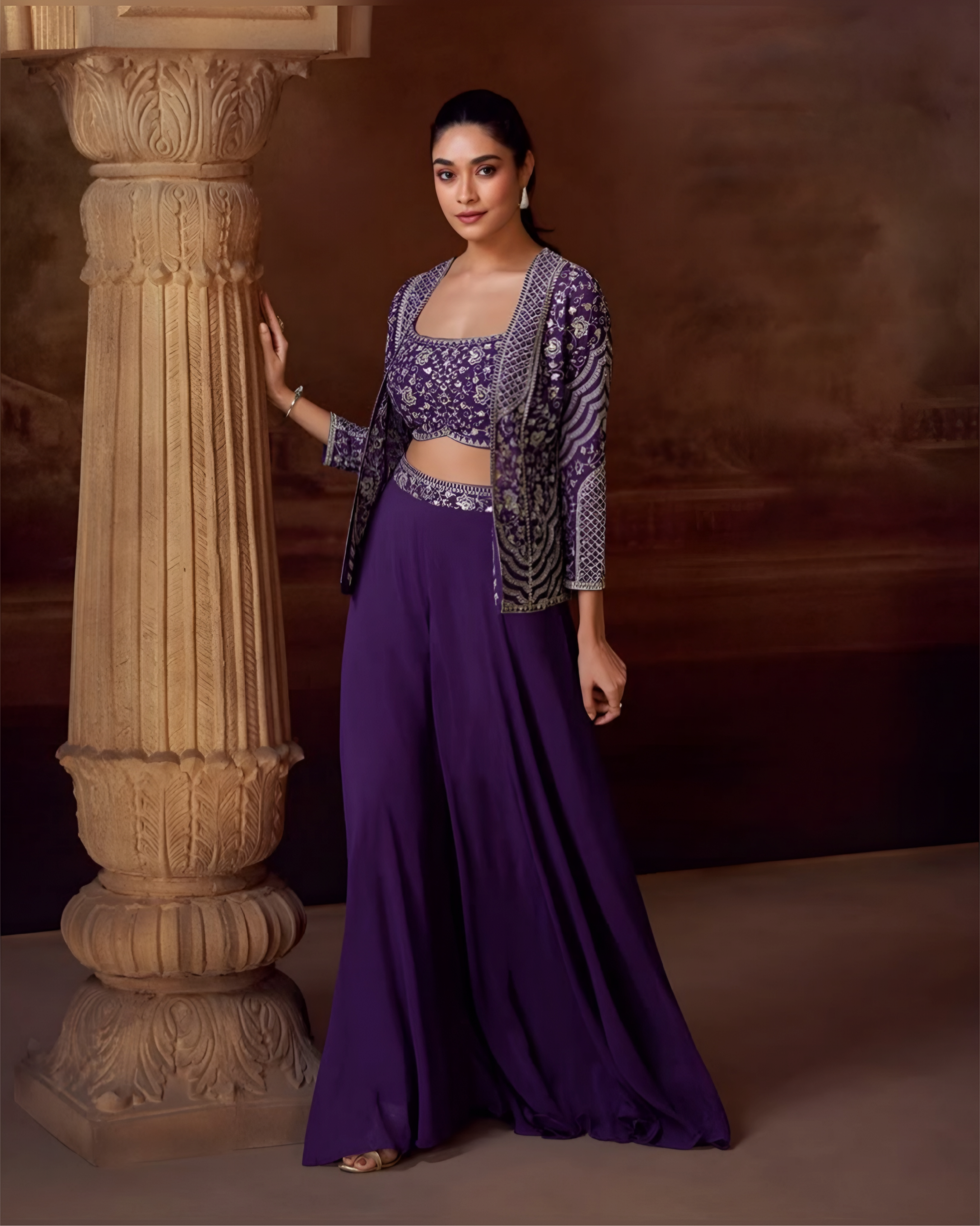 Woman in a purple traditional outfit standing next to an ornate column.