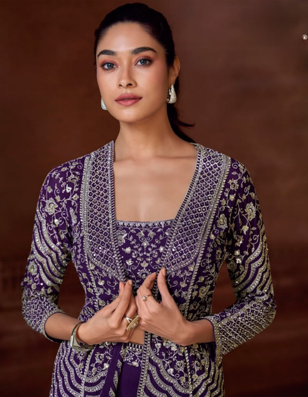 Woman wearing a traditional purple and gold outfit against a brown background