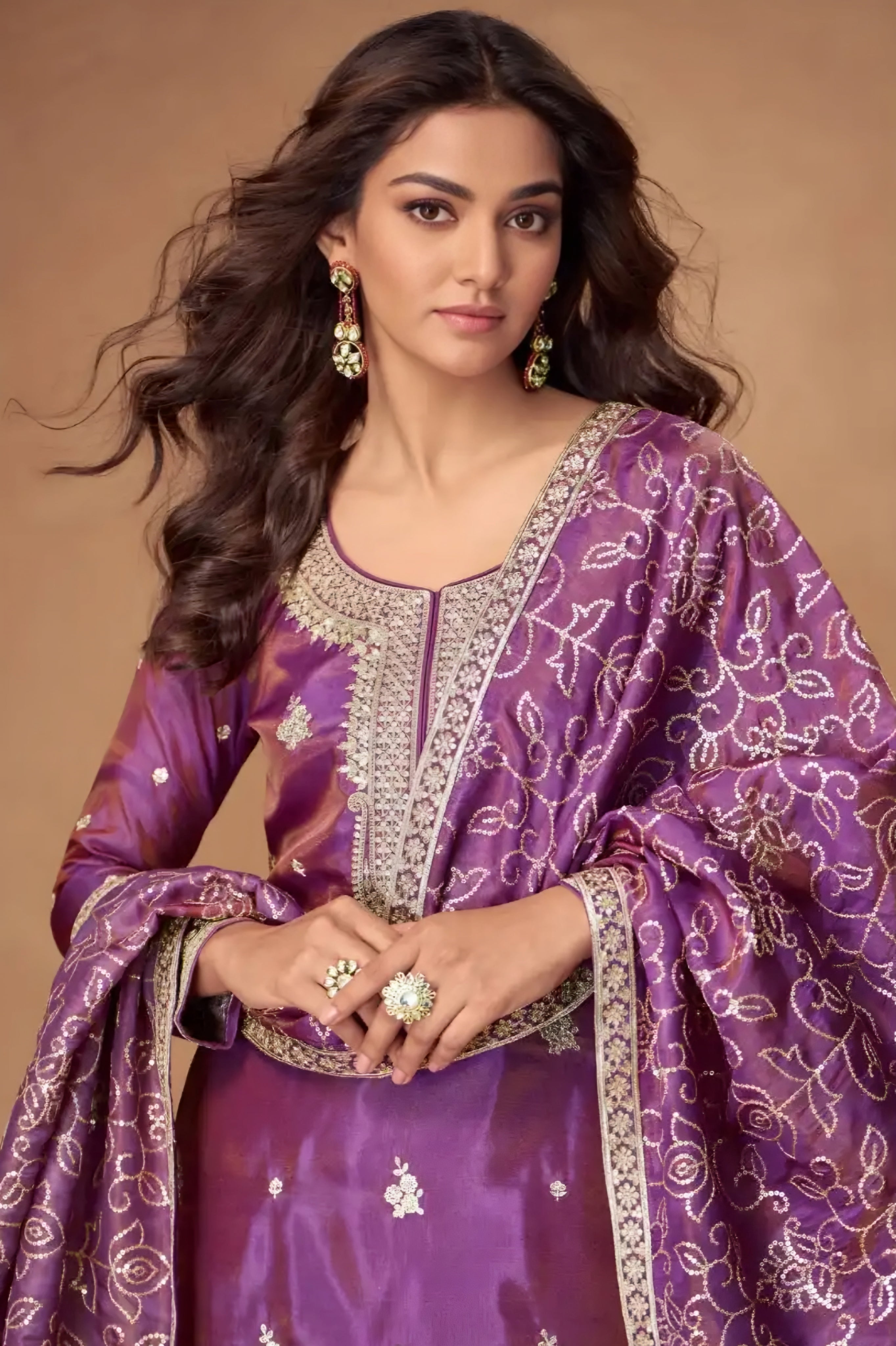 Woman wearing a purple traditional outfit with intricate patterns on a brown background