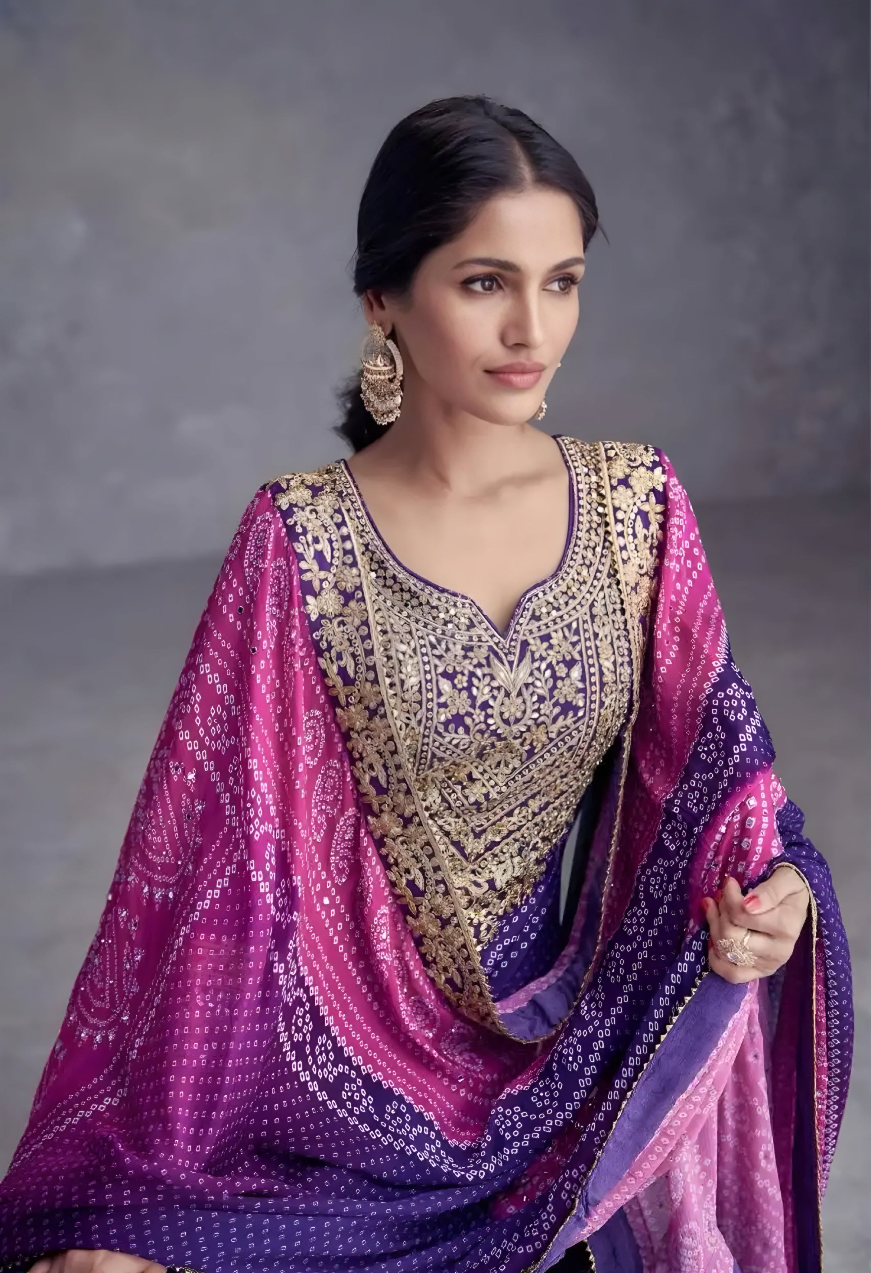 Woman wearing a traditional outfit with a purple and pink shawl against a gray background