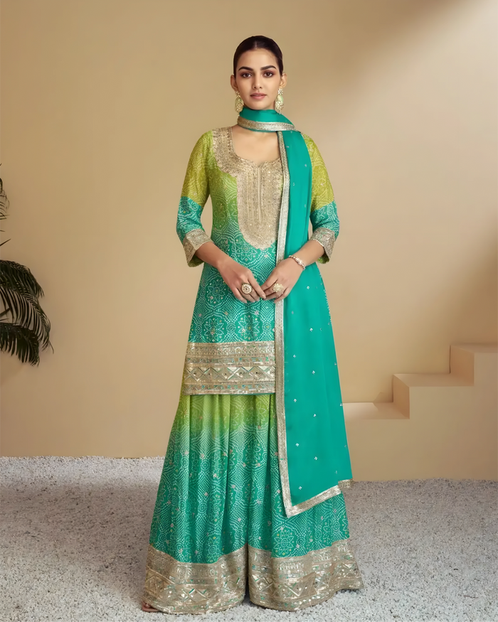 Woman wearing a green and teal traditional outfit with a matching dupatta on a beige background