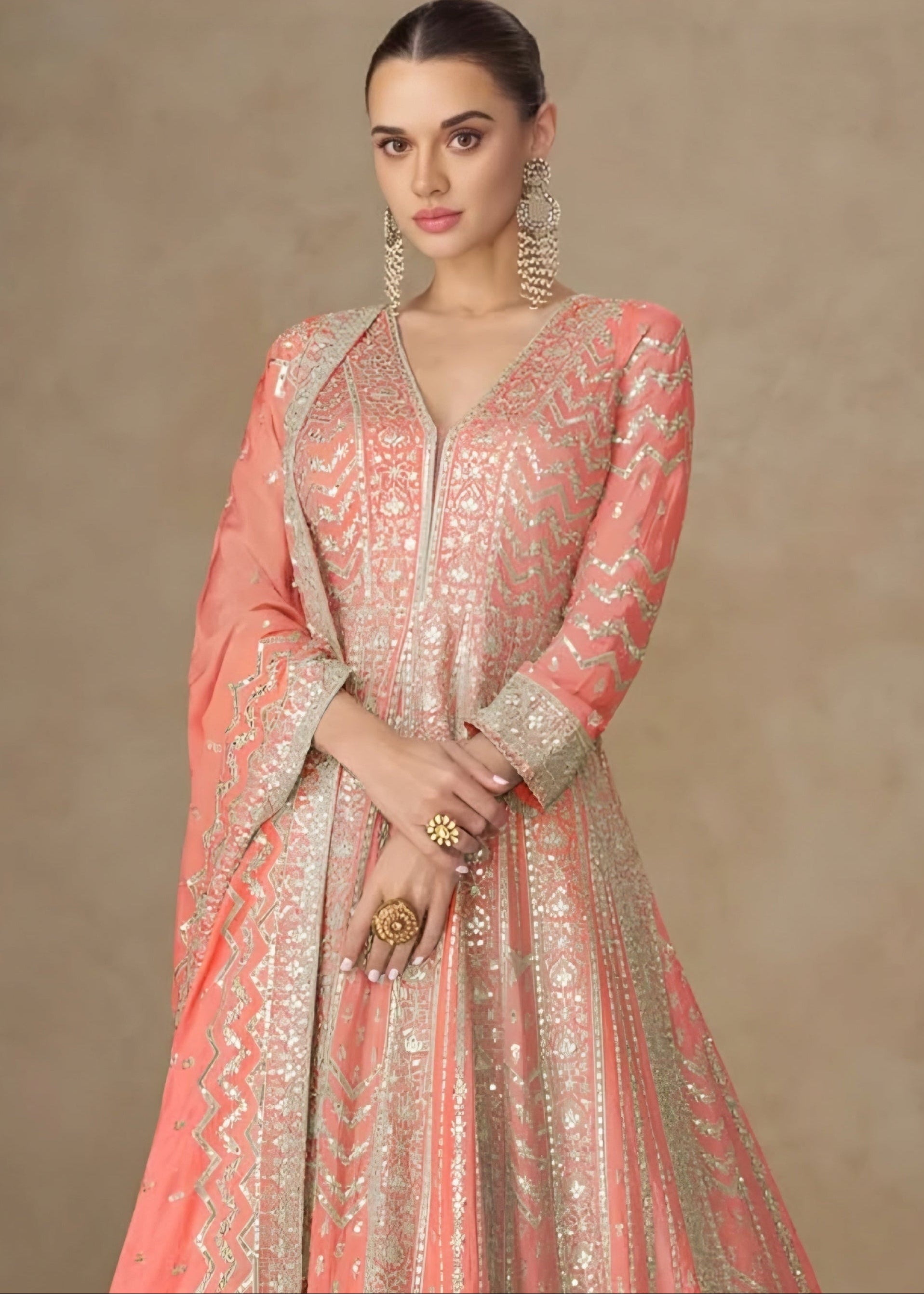 Woman wearing a pink and gold traditional outfit against a beige background